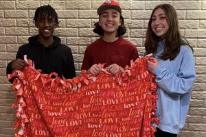 3 Faith Lutheran Church of McLean County youth hold a hand tied red fleece blanket for a resident at Carriage Crossing in Bloomington.
